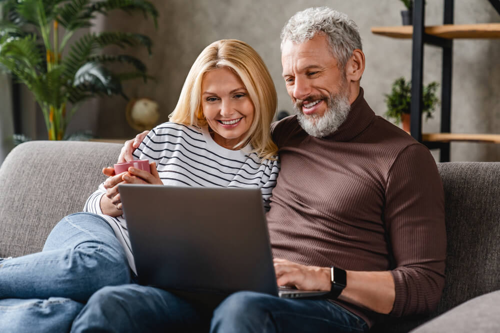 Beautiful middle aged couple using laptop and smiling